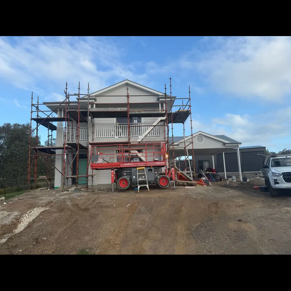Two-storey new home mid-build with scaffolding and access lift